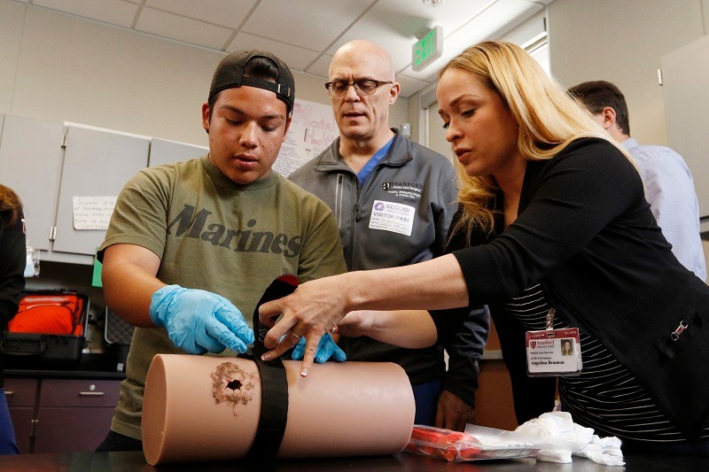 Student practicing tourniquet application on a training manikin arm in a Stop the Bleed class